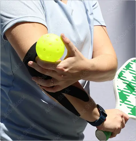 Person holding a tennis ball and racket while experiencing elbow joint pain, highlighting the need for professional joint pain evaluation and treatment at California Joint Pain Institute in Irvine, CA.