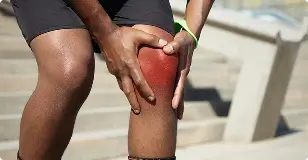 Person experiencing knee pain, illustrating the need for GAE treatment.